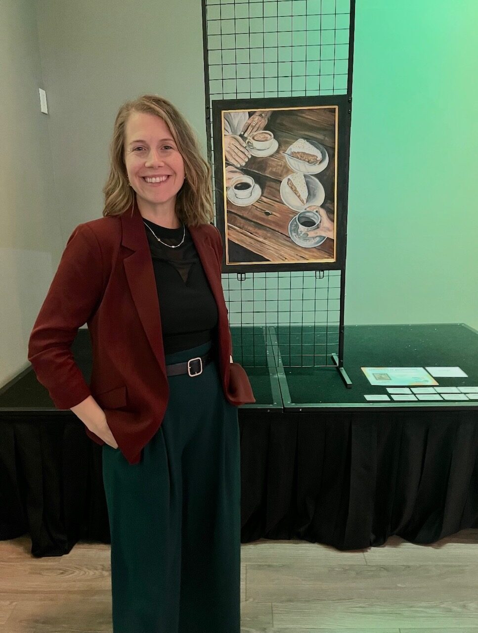 Nicole smiling beside Perspectives on its display stand at The Kim Foundation’s Night Out