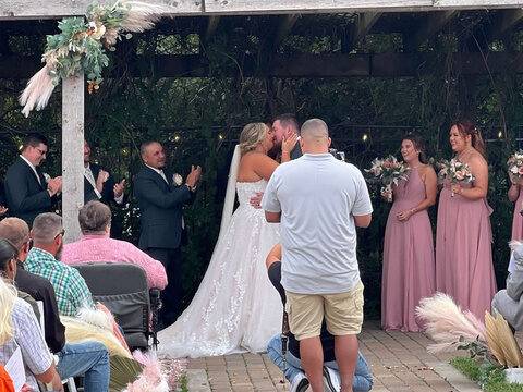 A bride and groom kissing under a pergola at the end of their ceremony