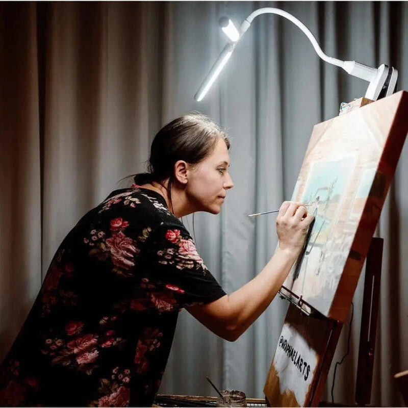 Nicole painting a wedding canvas on her easel under a clip-on lamp
