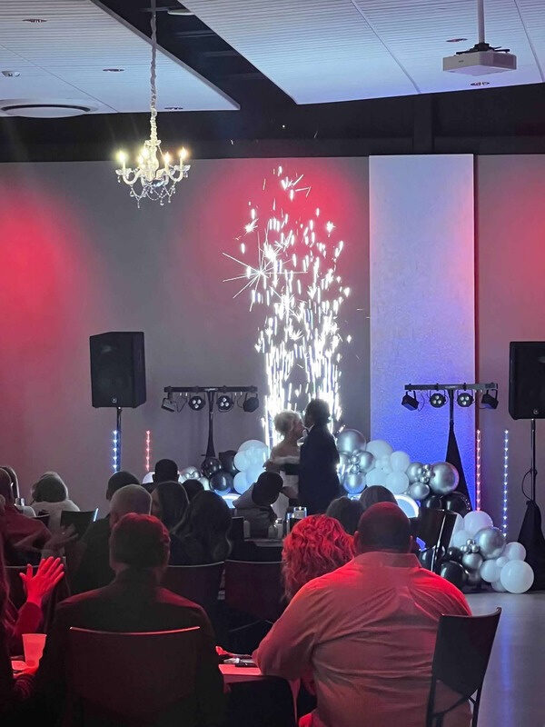 A couple dancing under a fountain of cold sparks while guests watch