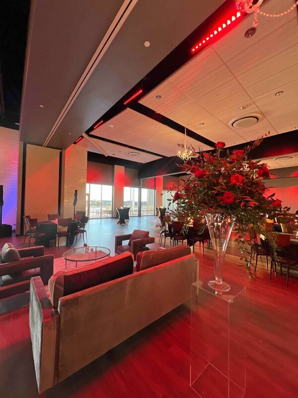 A reception room in red light with a tall arrangement of red roses