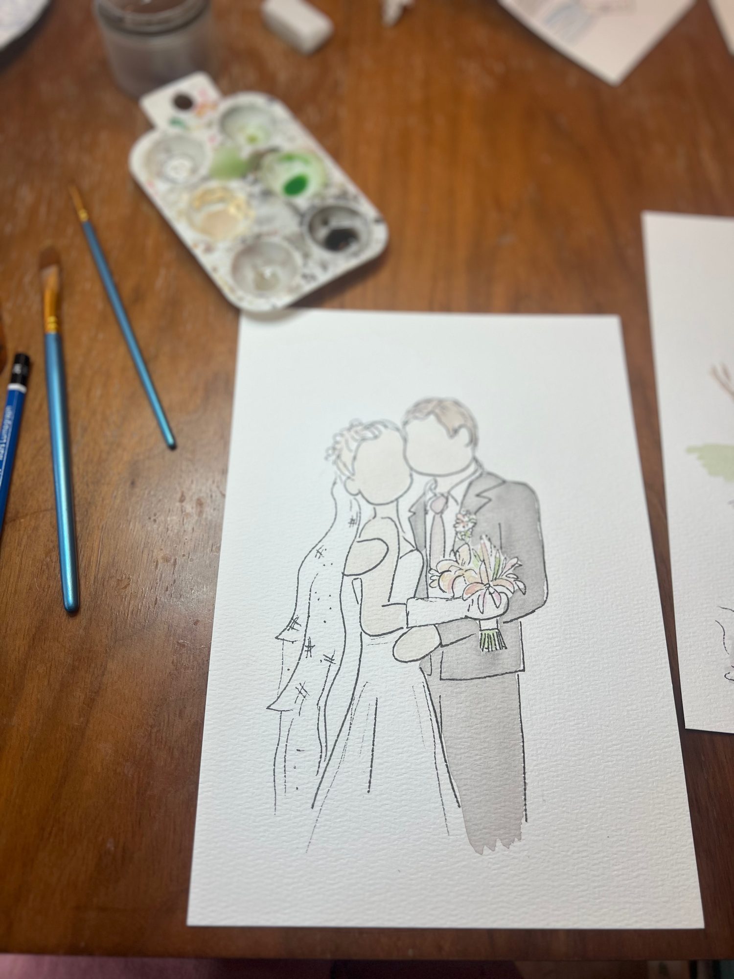 Ink sketch of a bride and groom mid-painting, brushes and palette alongside