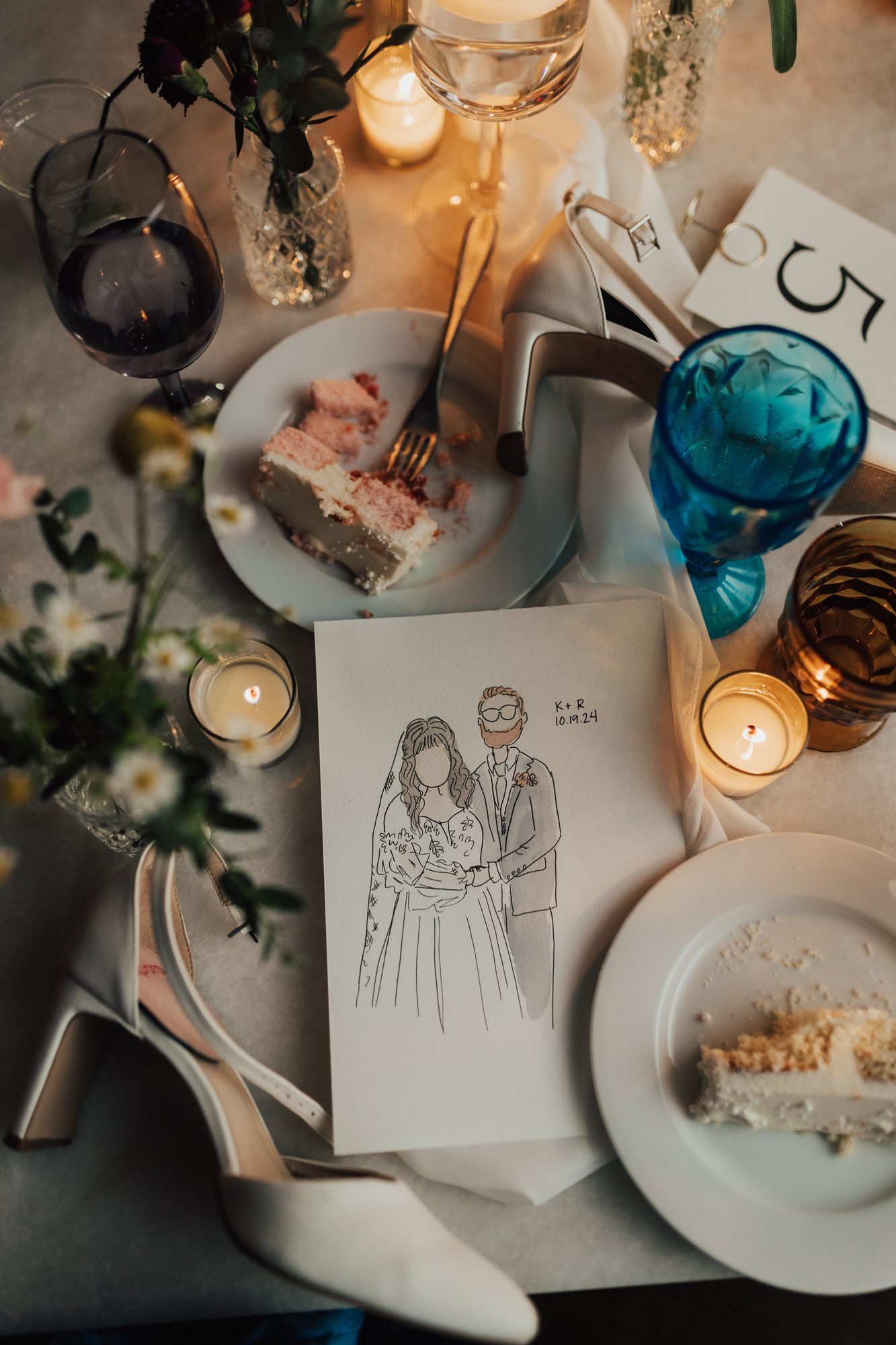 A finished mini portrait on a wedding table among cake, candles, and the bride’s shoes