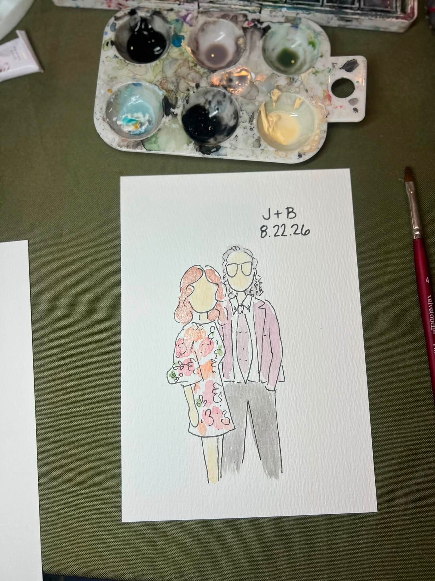 Mini portrait of a couple, she in a pink floral dress, on Nicole’s table with her paints